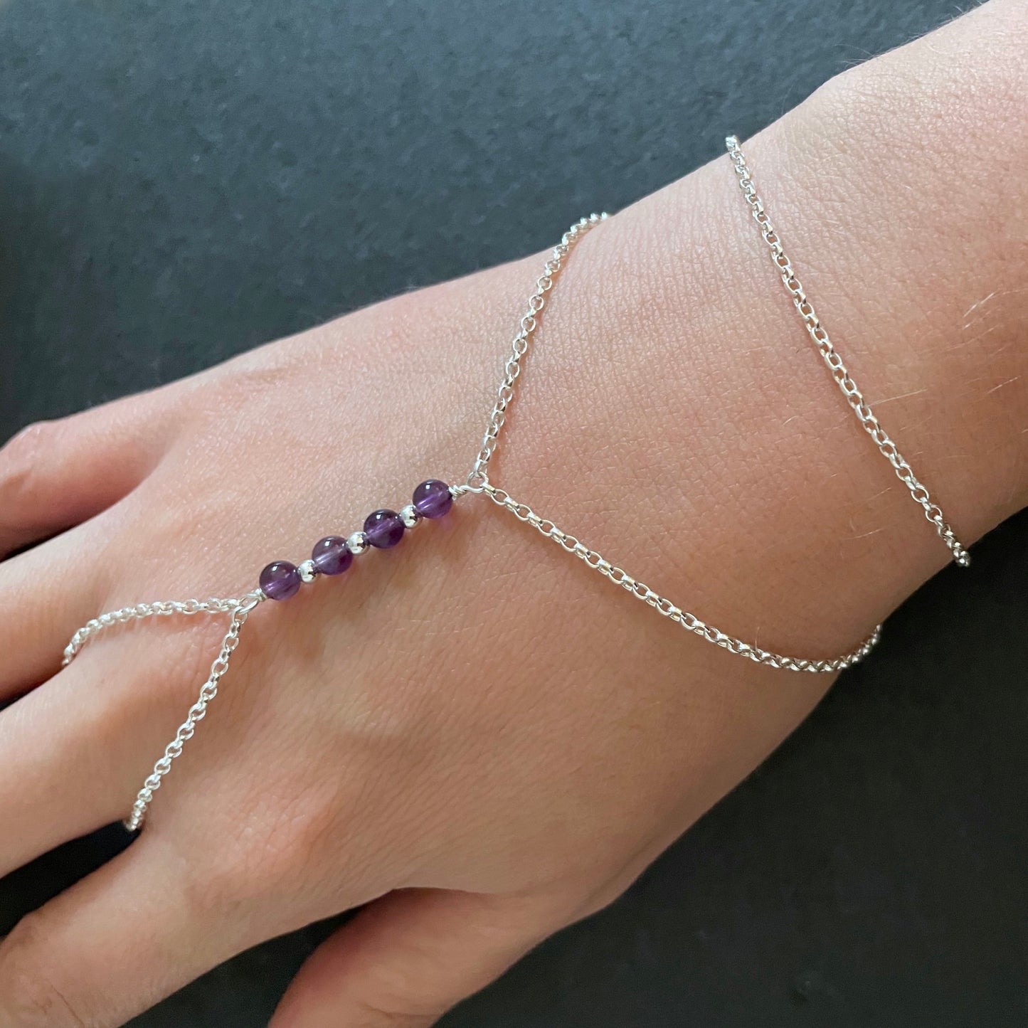 Sterling silver hand chain featuring Amethyst Beads on ahand