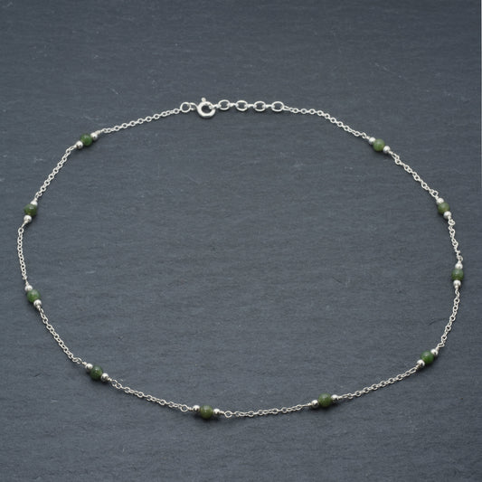 Jade and silver chain necklace on slate background