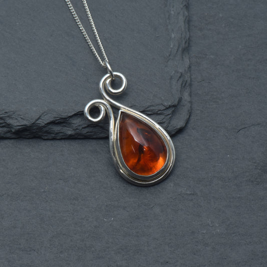 Teardrop Amber With a silver scroll design on a slate background