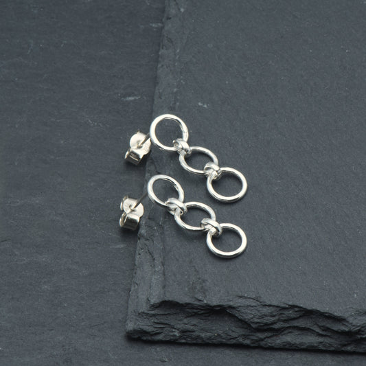 Hammered circle dangly earrings on a slate background