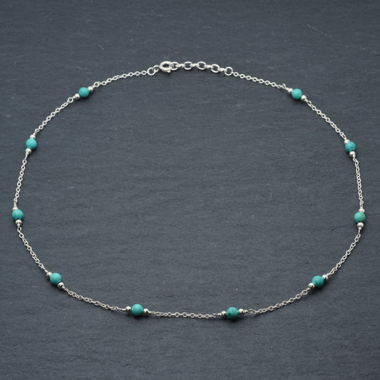 Turquoise bead and silver chain necklace on slate